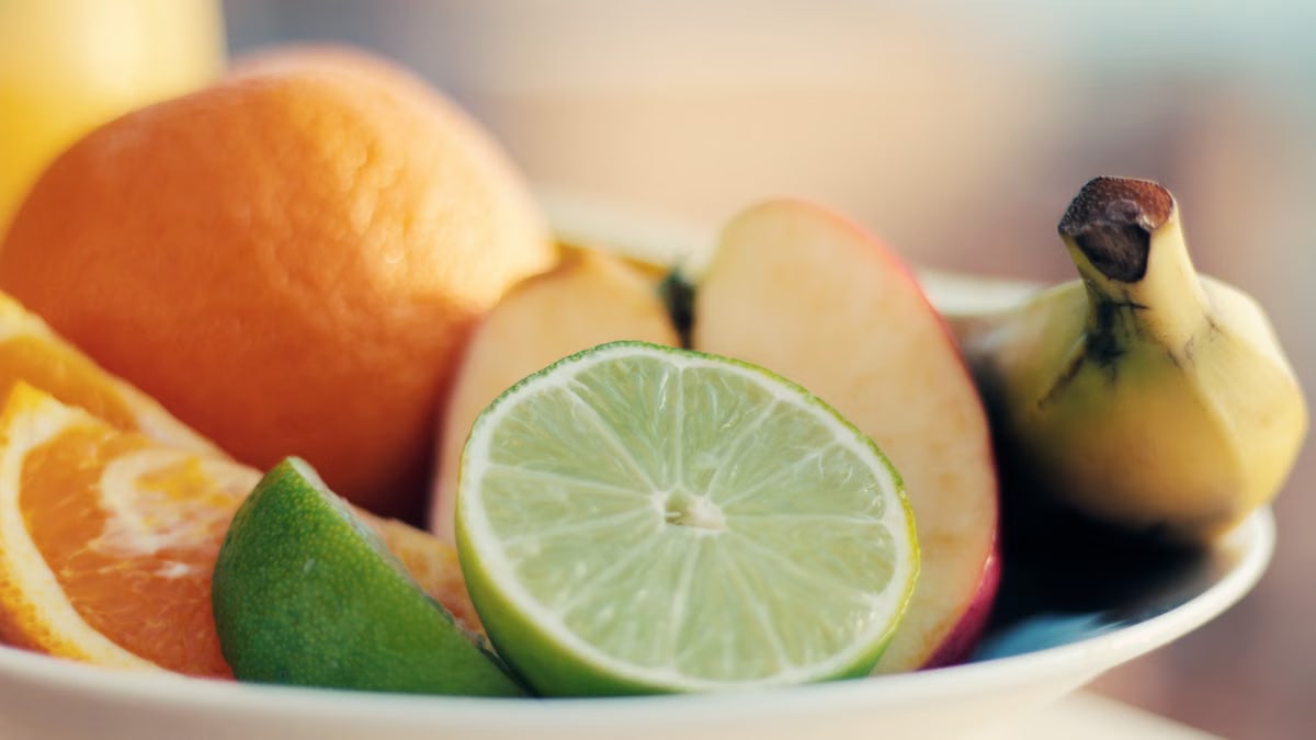 A close-up of a fresh mixed fruit bowl featuring citrus, banana, and apple slices for a healthy snack.